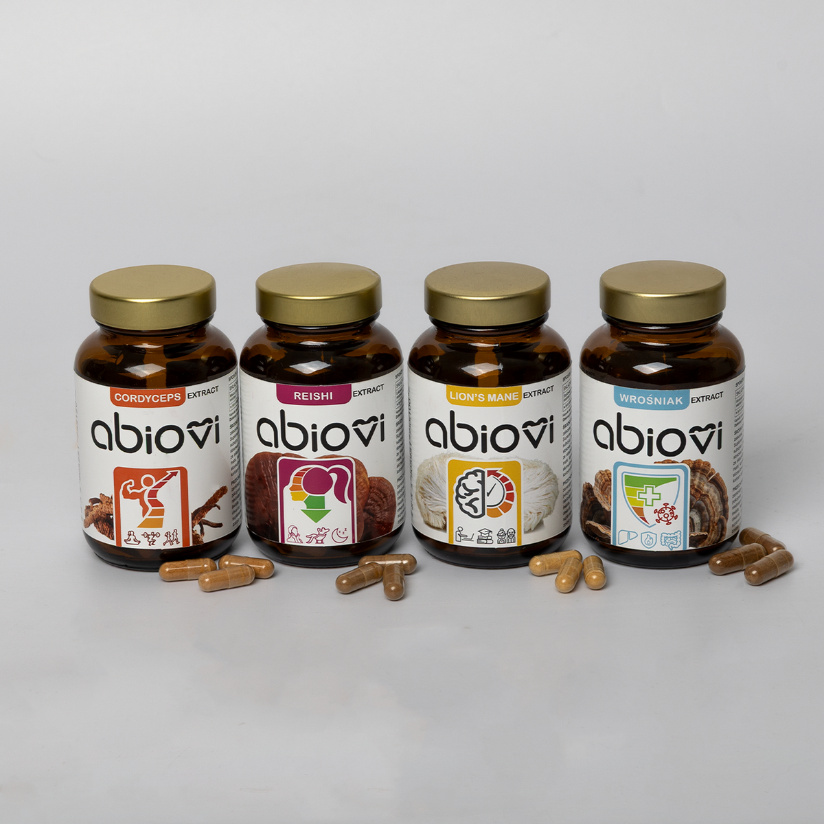 Zestaw 4 ekstraktów Abiovi: Cordyceps, Reishi, Soplówka jeżowata i Wrośniak z rozsypanymi kapsułkami.